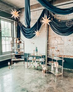 a room filled with lots of tables covered in blue draping and stars hanging from the ceiling