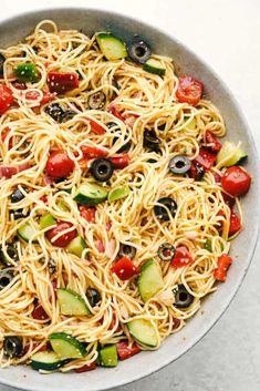 a pan filled with pasta and veggies on top of a white tablecloth