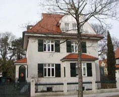 a white house with green shutters and red roof