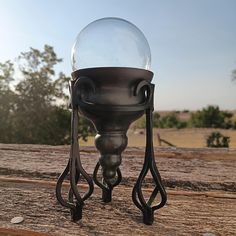 a glass ball sitting on top of a metal stand in the middle of a wooden deck