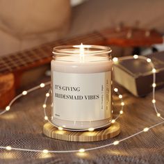 a candle sitting on top of a table next to a string of lights and a guitar