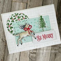 a christmas card with a horse and holly tree on it, in front of a wooden background