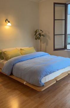 a bed sitting on top of a hard wood floor next to a window in a bedroom