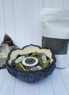 a bowl filled with dirt and plants next to a bag of black seeding powder