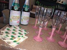 wine glasses and napkins are sitting on a table with pink glittered confetti