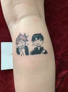 a person with a tattoo on their arm that has an image of two people sitting next to each other