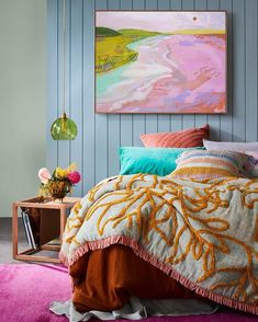 a bedroom with blue walls, pink carpet and colorful artwork on the wall above the bed