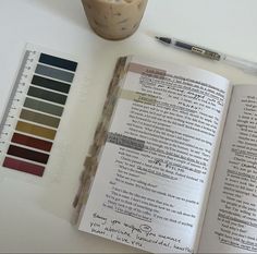 an open book sitting on top of a white table next to a cup of coffee