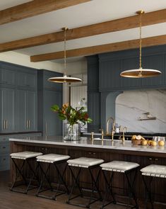 a large kitchen with blue cabinets and marble counter tops, along with four stools