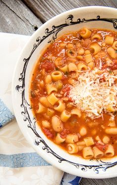 a white bowl filled with pasta and sauce on top of a blue and white napkin