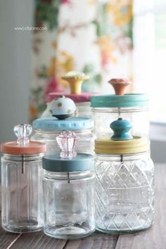 four glass jars with lids are lined up on a table