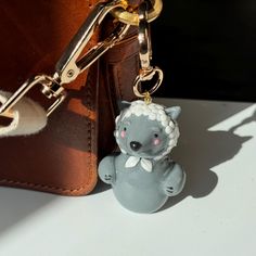 a keychain with a small toy bear on it's side next to a purse