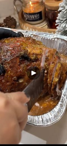 a person cutting up food in a foil pan