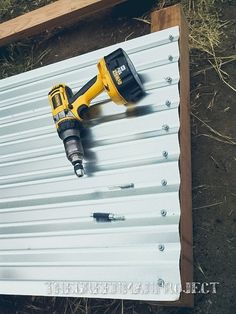 a drill is laying on top of a metal sheet with screwdriver attached to it