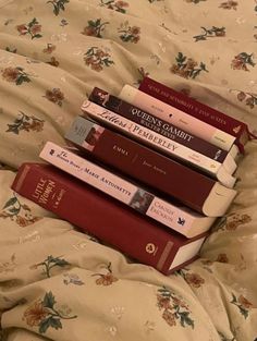 a stack of books sitting on top of a bed next to each other in front of a pillow