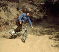 a man riding a bike down a dirt road