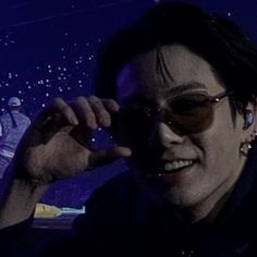 a man wearing sunglasses is smiling and making a peace sign with his hand in front of him