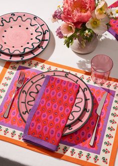 the table is set with pink and purple placemats, napkins, and utensils