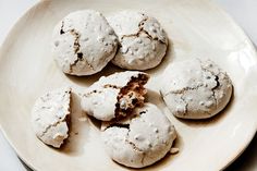 four cookies are on a white plate and one is half eaten