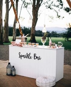 a table with food and drinks on it at a wedding or other outdoor event in front of some trees