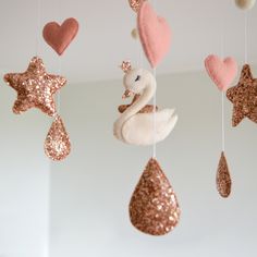 some pink and gold ornaments hanging from the ceiling with hearts, stars, and swans