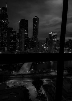 black and white photograph of city skyline at night from an apartment window with dark clouds