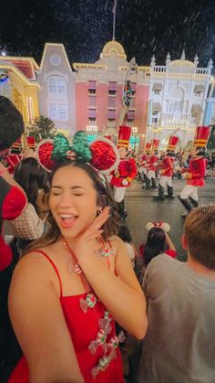 a woman in a red dress standing next to a group of people with christmas decorations on their heads