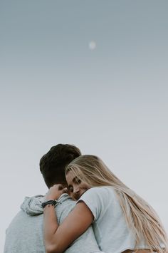 a man and woman embracing each other in front of the sky