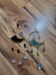 two necklaces are hanging on a wooden floor next to other jewelry and accessories,