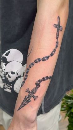 a person with a tattoo on their arm holding a cross and a chain attached to it