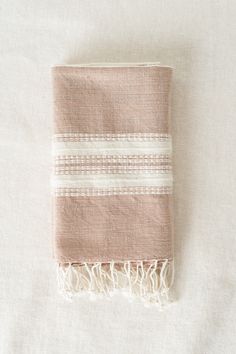 a pink and white striped towel laying on top of a bed next to a pillow