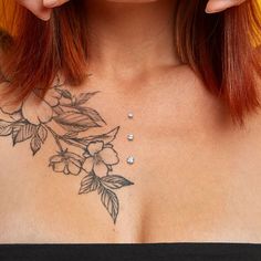 a woman's chest with flowers and leaves tattooed on her chest, while she is looking at the camera