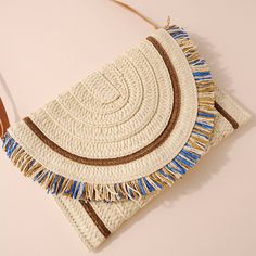 Raffia woven clutch bag with fringe detail, button closure, and bag strap. Approx: 11" x 8.3" Material: 100% paper Beach Crossbody Clutch With Adjustable Strap, Summer Beach Crossbody Clutch, Spring Rectangular Shoulder Bag With Fringe, Chic Shoulder Bag With Fringe For Spring, Chic Spring Shoulder Bag With Fringe, Chic Fringe Shoulder Bag For Spring, Chic Fringed Shoulder Bag For Spring, Chic Straw Bag With Fringe, Vacation Straw Clutch Bag With Adjustable Strap