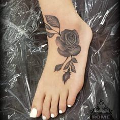 a woman's foot with a rose tattoo on it