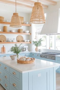 a kitchen with blue cabinets and wicker baskets hanging from the ceiling over the island