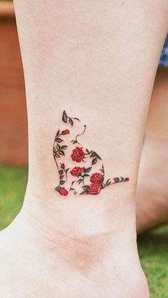 a woman's foot with roses on it and a cat in the middle tattoo