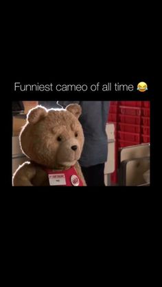 a brown teddy bear sitting on top of a table next to a red sign that says funniest came of all time