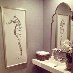 a bathroom with a sink, mirror and seahorse artwork on the wall above it