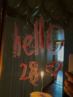 a person holding a cell phone in front of a window with the words hello 28 written on it