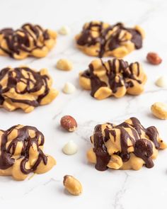 chocolate and peanut butter cookies with nuts scattered around them on a white marble countertop