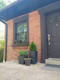 two planters on the side of a brick building next to a door and window