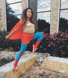 a woman dressed as a super hero is posing for a photo in front of a building