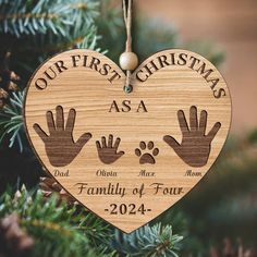 a wooden ornament with two hands and the words our first christmas as a family of four