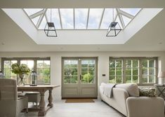 a living room filled with furniture under a skylight next to a table and chairs