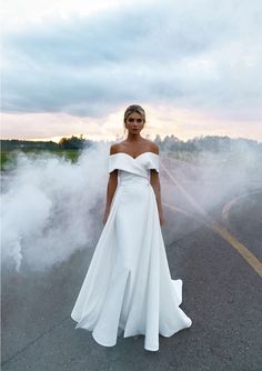 a woman standing in the middle of a road wearing a white dress