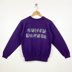 90s South Dakota Crewneck Sweatshirt Print Logo Purple Color Women's S - Made in Mexico  Materials : Cotton, Polyester  - Tag Reads : Women's S Kindly see the actual measurements (All measurements were taken lying flat) - Actual size manual measurements * Width (Armpit to armpit) : 19 inches * Length (Shoulder to end of garment) : 24 inches * Sleeve length : 21 inches - Condition : * Good condition 8/10 (80%) * Minor stain refer picture * Free from tear and major defect - Shipping : * DHL Express/FedEx Express = 3-6 business day arrived * Please PROVIDE your PHONE/CONTACT NUMBER for SHIPPING/DELIVERY purpose DON'T FORGET TO VISIT MY SHOP FOR MORE GREAT STUFF, THANK YOU. Purple 90s Style Tops For Fall, Purple 90s Style Top For Fall, Vintage Purple Sweatshirt For Fall, Purple Vintage Sweatshirt For Fall, 90s Style Cotton Sweater, 90s Style Relaxed Fit Cotton Sweater, 90s Relaxed Fit Cotton Sweater, Retro Long Sleeve Purple Sweatshirt, Retro Purple Long Sleeve Sweatshirt