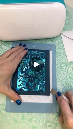 two hands are using a tablet to draw designs on the screen while another hand is holding a pen