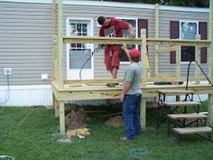 two men are working on a deck in the yard