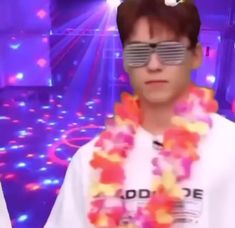 a man wearing sunglasses and a lei around his neck in front of a purple light