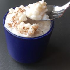 a blue cup filled with whipped cream and topped with cinnamon sprinkles on a black surface